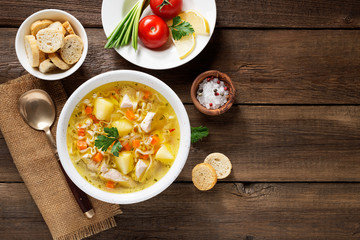 Chicken soup with noodles and vegetables in white bowl on  wooden background