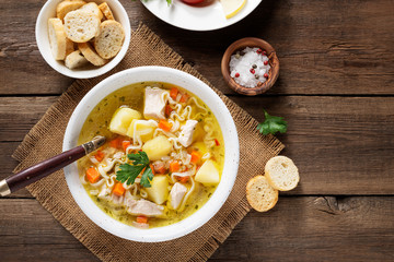 Chicken soup with noodles and vegetables in white bowl on  wooden background