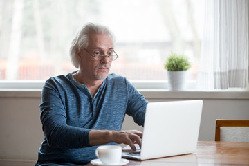 Surprised aged man stunned getting error or mistake message working at laptop, senior male using pc shocked by unexpected computer problem or virus attack, elderly amazed reading news online