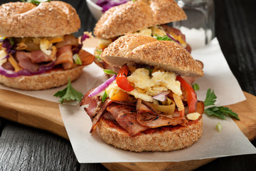 Sandwiches with fried bacon ,vegetables and fried egg on wooden board