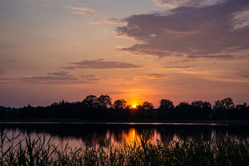 Naklejka premium colorful sunset on the lake with water reflections and dramatic storm clouds above
