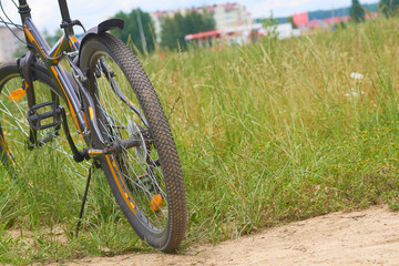 Fototapeta na wymiar A black bicycle in the panoramic view of green field.