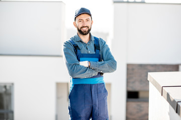 Portrait of a builder in uniform on the roof of a new white building outdoors