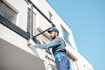 Builder in blue uniform mounting aluminium fence on the balcony of the new building