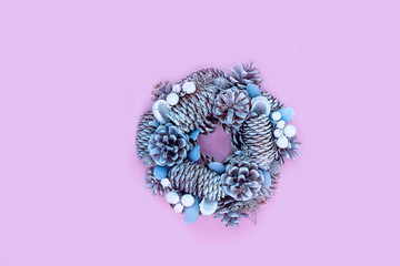 Winter and Christmas wreath with snow covered spruce pine fir, mistletoe, pine cones, cedar isolated on pink background.