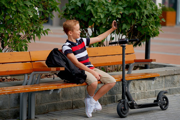 Happy smiling school boy with backpack and electric scooter outdoors. Childhood, leisure, school and people concept