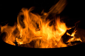 Fototapeta premium Beautiful flame with sparks in bonfire in the night. Heat and danger energy concept. Fire in darkness. Inferno and element concept. Campfire with bright flame. Fire in motion on black background. 
