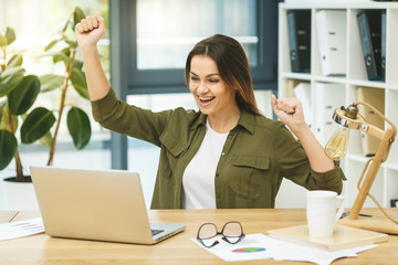I am a winner! Portrait of young cheerful business woman in smart casual wear having fun and...