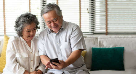Happy Asian senior Couple using smartphone.