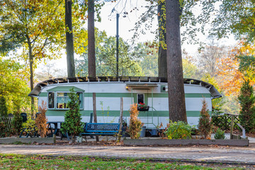 Retro white green caravan at a campsite in the middle of the forest.