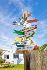 wooden pole guidepost with multiple destinations of the world on arrows sticks (white, yellow, red...