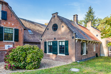 Fototapeta na wymiar Idyllic Dutch farmhouse with black red roof tiles and green shutters