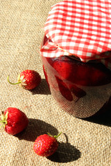 jar with strawberry jam and berries on the sacking