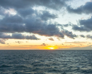 A sunset at sea with dramatic puffy clouds