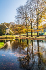 Obraz premium Historic Dutch scene with wooden barn and windmill in the open air museum in Arnhem in the Netherlands