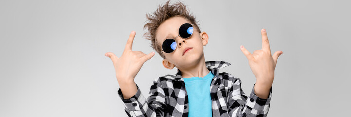 blue shirt and jeans stands on a gray background. The boy is wearing round glasses. Redhead boy...