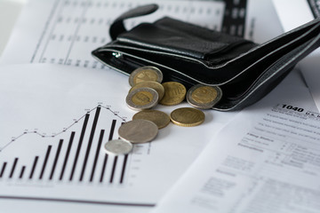 The black wallet with coins are on tax papers and finances diagram