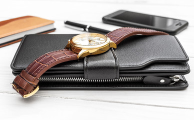 Men's accessories on wooden table. Purse, wrist watch, smartphone and notepad.