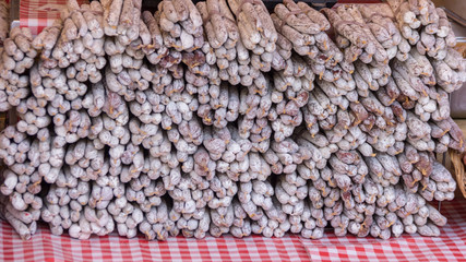 Stacks of cured sausages sitting on a checked table cloth