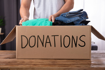 Man Donating Clothes In Donation Box