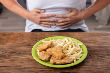 Fried Food In Front Of Person Having Stomach Pain