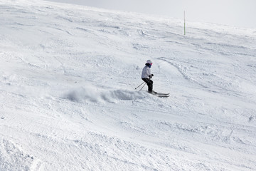 Fototapeta na wymiar Skier downhill on snowy ski slope at suny winter day