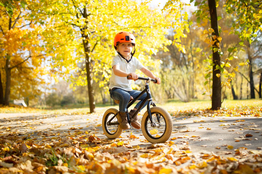 Image of boy in helmet on running bike in autumn park