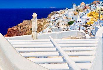 View of the city of Santorini island through the white roof of the hotel. Bright sunny day, the sea, the famous stairs and the slope with the port.