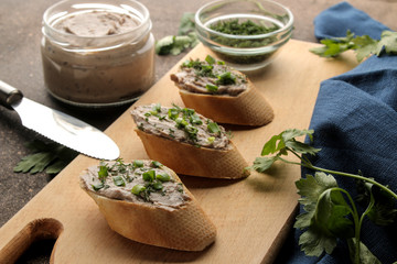 Fresh homemade chicken liver pate with greens on bread on a dark background. A sandwich.