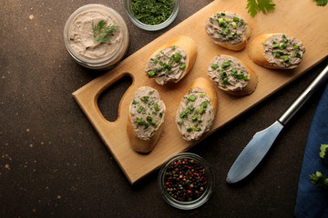 Fresh homemade chicken liver pate with greens on bread on a dark background. view from above