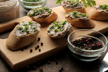 Fresh homemade chicken liver pate with greens on bread on a dark background. A sandwich.