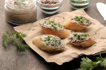 Fresh homemade chicken liver pate with greens on bread on a dark background. A sandwich.