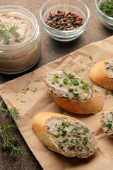 Fresh homemade chicken liver pate with greens on bread on a dark background. A sandwich.