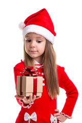 Happy christmas girl looking at the gift holding it in the hand, wearing a santa hat isolated over a white background