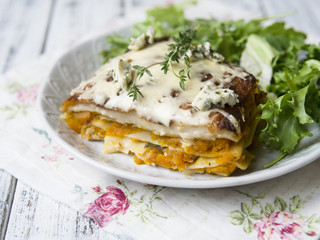 Slice of Pumpkin and Spinach Lasagne with blue cheese and salad on a White Wooden Table. Selective focus, copy space, closeup