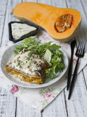 Slice of Pumpkin and Spinach Lasagne with blue cheese and salad on a White Wooden Table. Selective focus, copy space, closeup