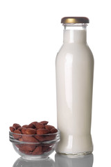 Fresh almond milk in a glass bottle and nuts of almonds closeup on a white isolated background.