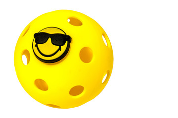 Pickleball Vacation...Yellow Pickleball with attached sun glasses and smile on white background..