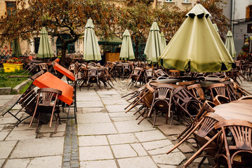 Cafe tables and chairs outside with large green umbrellas. Old beautiful city