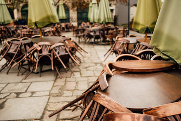 Cafe tables and chairs outside with large green umbrellas. Old beautiful city