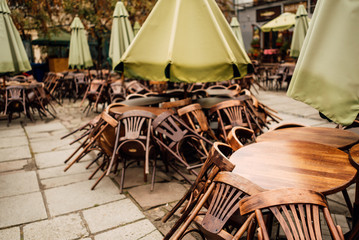 Cafe tables and chairs outside with large green umbrellas. Old beautiful city