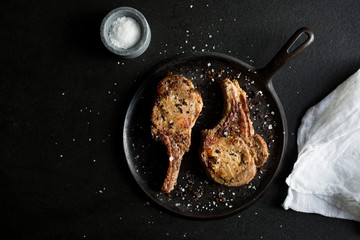 Overhead view of baked pork chops against black background