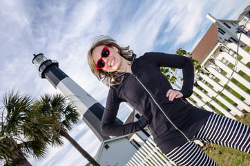 Tybee Island Light House in coastal Georgia, portrait of a woman standing smiling with hands on hips. Artistic angle