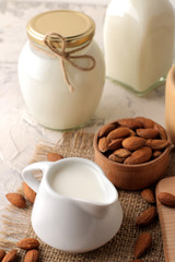 Obraz na płótnie Canvas Fresh almond milk in a milk jug and almond nuts on a light background