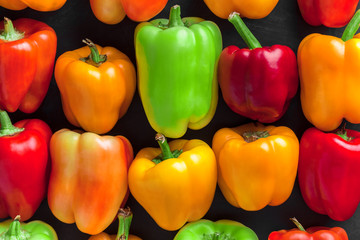 Bell peppers arrangement lined up overhead close up large colorful mix on dark background studio shot