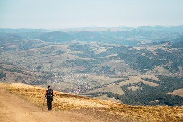 Obraz premium Man traveler walking along the road. There are mountains on the horizon. The sky is blue and cloudy.