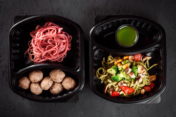 pink pasta with steamed pasta and green pasta with vegetables in eco boxes. on a black background. Healthy food delivery. Vegetarian dish. Vegetarian Delivery.