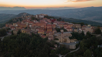Fototapeta na wymiar Aerial view at sunset of the small town of Montecalvo Irpino, in the province of Avellino, in Italy. This village with few houses and streets is built in the mountains of Irpinia.