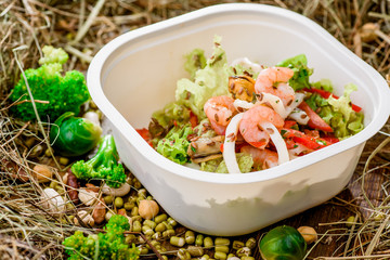 Salad with shrimp. Healthy food delivery. Take away for diet. Fitness nutrition, vegetables, meat and fruits in eco boxes. at wood and straw with copy space. series of photos