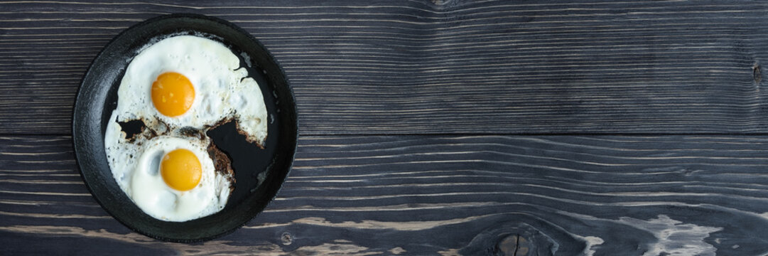 fried eggs on a cast-iron pan on an old wooden gray background